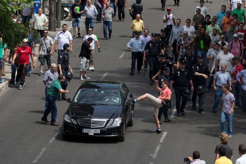 A demonstrator kicks a car, suspected to be a private taxi during a 24 hour taxi strike and protest in Madrid, Spain, Wednesday, June 11, 2014. The taxi drivers were protesting against unregulated competition from private companies, in particular, Uber, an international company that puts people in contact with each other to share cars or pay for short journeys in private vehicles within the city. (AP Photo/Paul White)